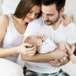 Akcesoria dla niemowląt - matka z ojcem trzymająca dziecko